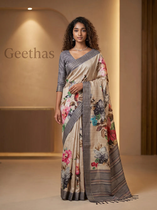 Model wearing a beige semi tussar saree with multicolour floral prints and a grey striped border