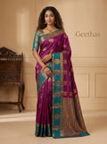 Model wearing a magenta pink soft silk saree with gold-toned woven motifs, teal border and ornate pallu