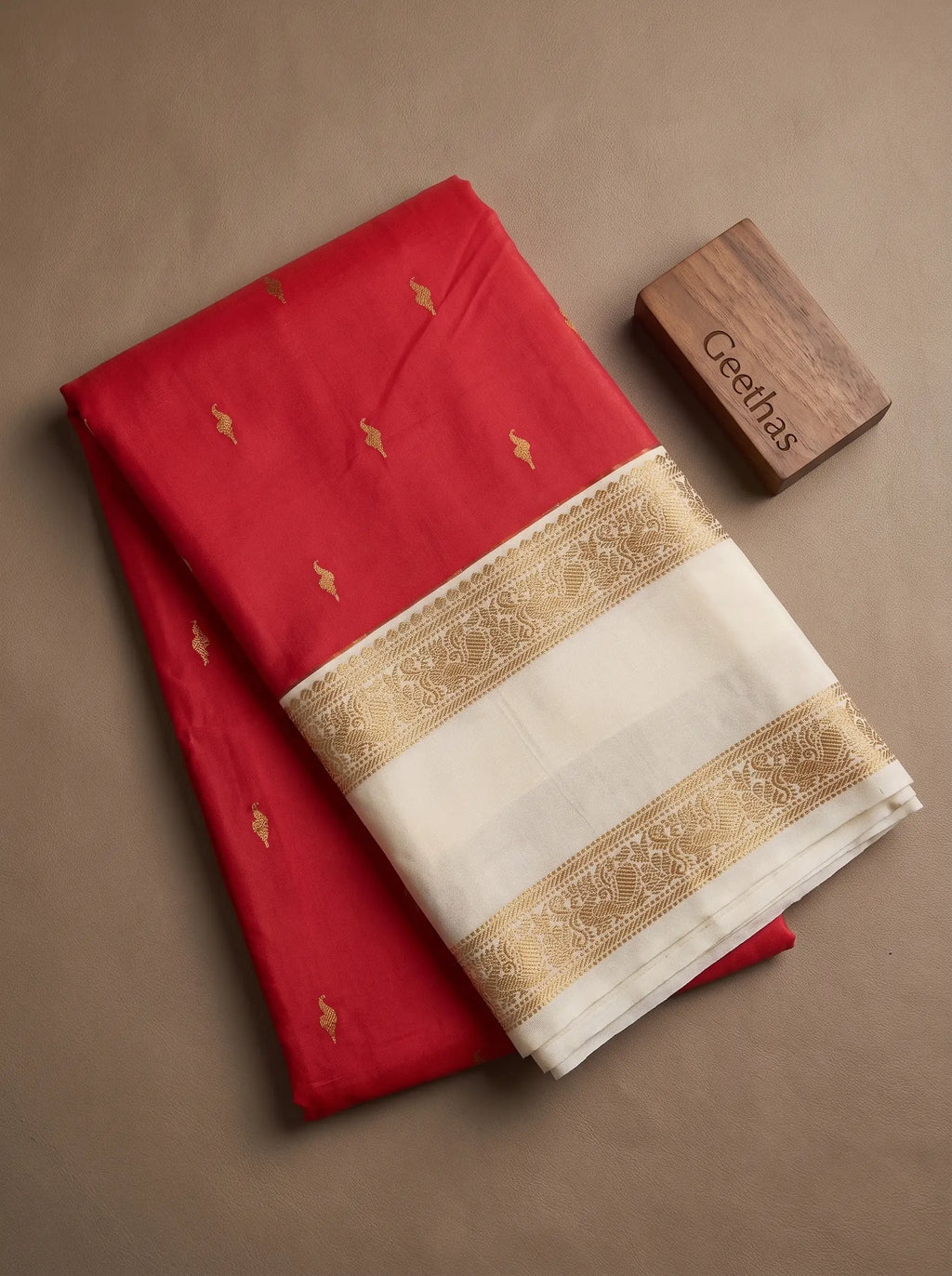 Folded bright pink soft silk saree with gold-toned motifs and ivory decorative border