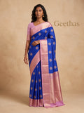 Model wearing royal blue soft silk saree with gold-toned woven motifs and pink border