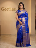Model wearing a royal blue soft silk saree with gold-toned woven floral motifs and an ornate border